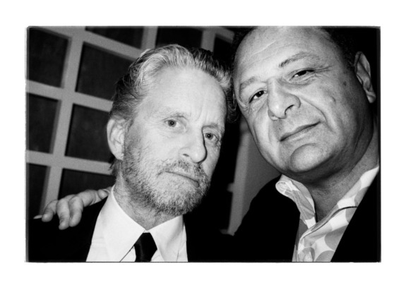 Two men posing together at an event, one with a beard and suit, the other with a light shirt and jacket, black and white photo