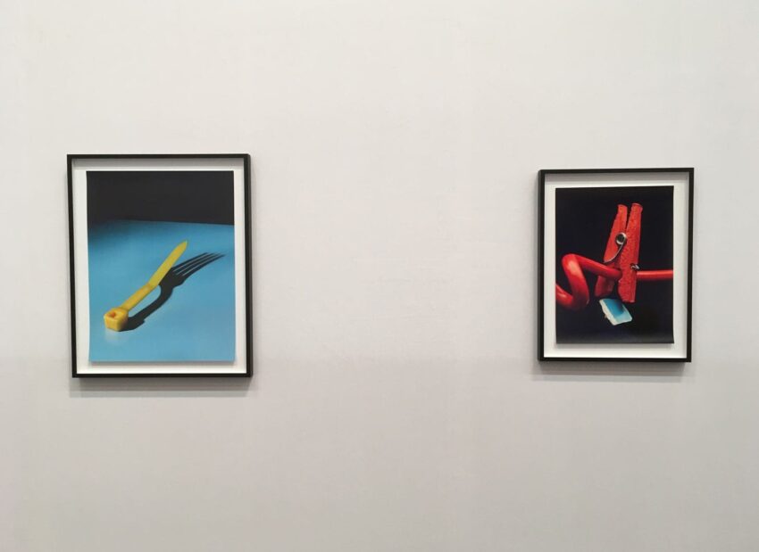 Two framed art pieces on a gallery wall, featuring objects creatively posed against contrasting backgrounds.