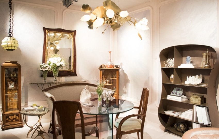 Elegant room with vintage furniture, glass table, stylish chandelier, mirror, and decorative shelves.