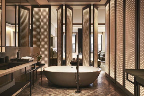 Luxurious modern bathroom with a freestanding bathtub, wooden flooring, and decorative paneling for an elegant atmosphere.