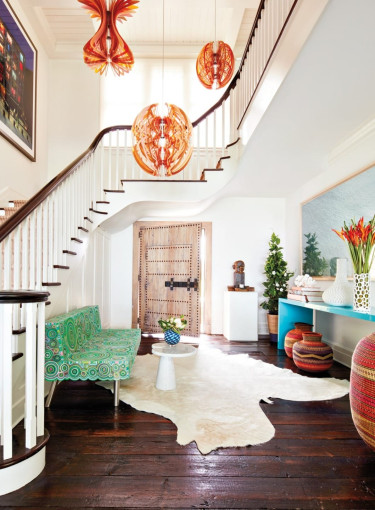 Eclectic living room with vibrant decor, colorful chandeliers, patterned seating, wooden floors, and unique art pieces.