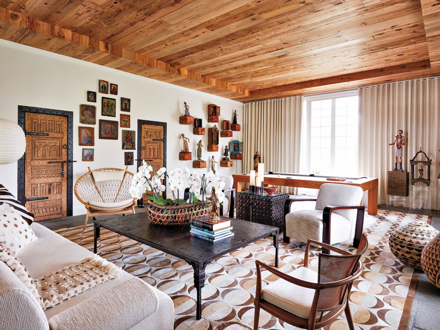 Cozy living room with wooden ceiling, modern furniture, patterned rug, and decorative artwork on walls.
