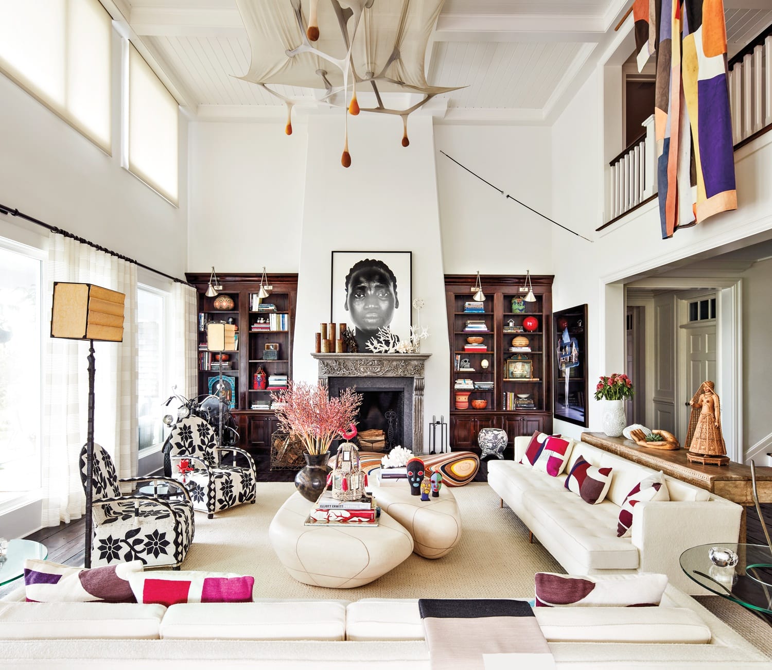 Eclectic living room with modern furniture, large artwork above fireplace, and colorful decor accents throughout the space.
