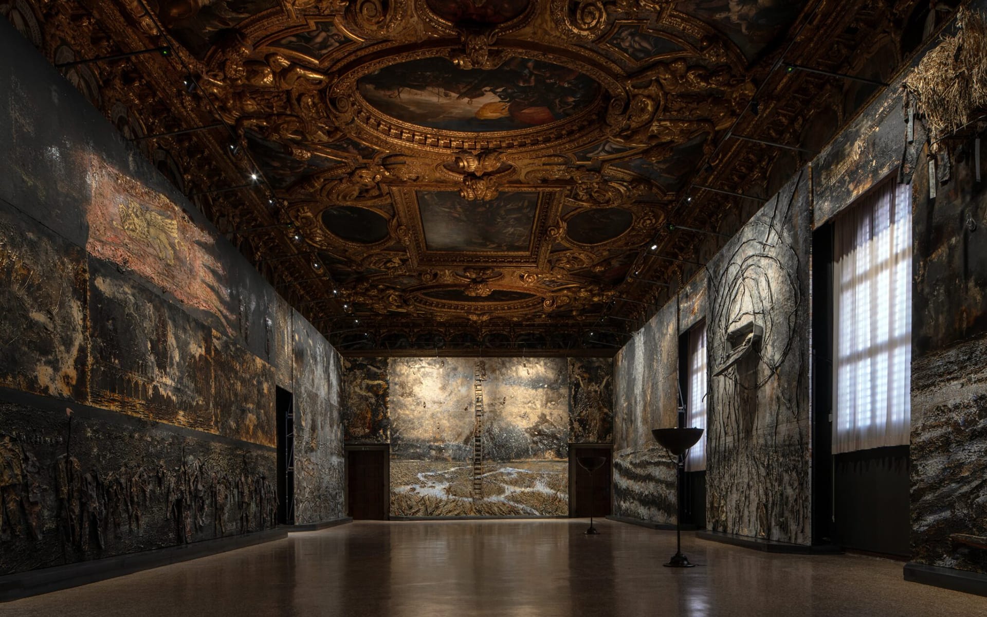 Ornate museum hall with detailed ceiling art, textured wall displays, and soft lighting illuminating the large interior space.