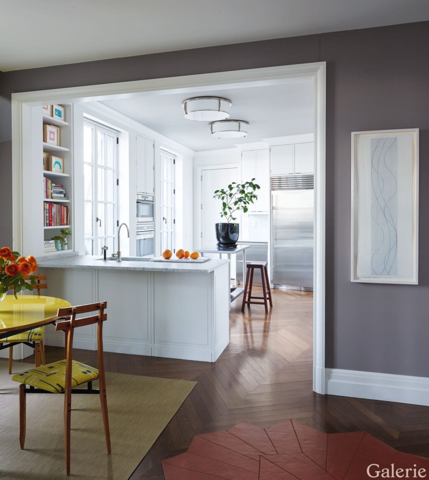 Stylish contemporary kitchen with white cabinetry, modern lighting, and a small dining area with orange flowers on the table