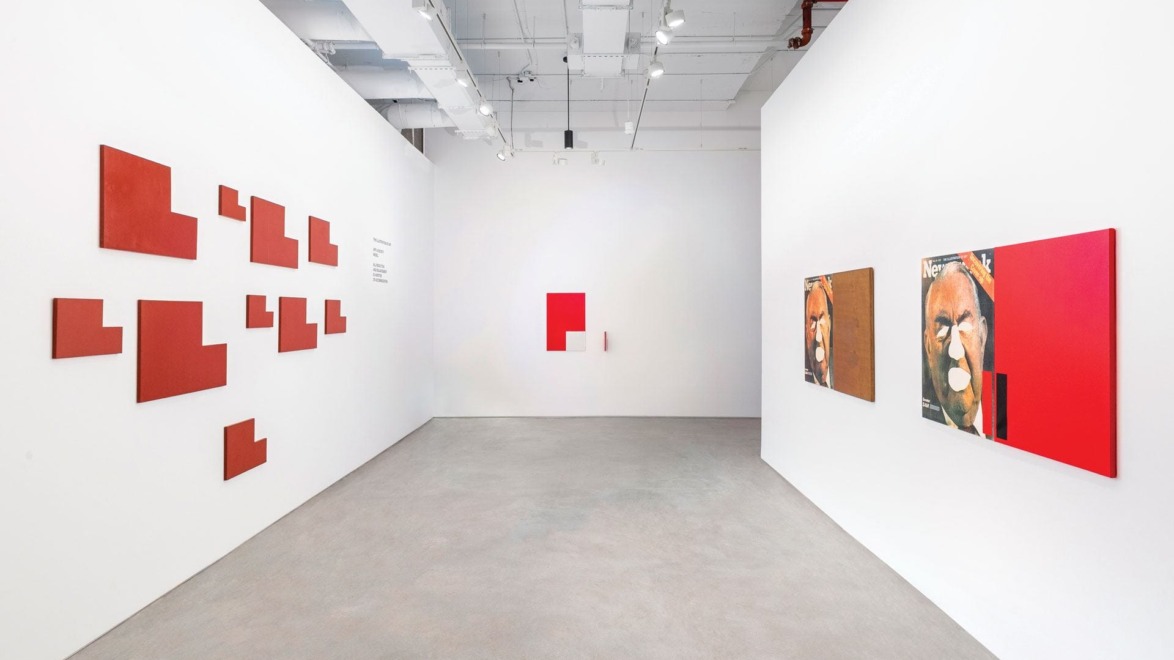 Art gallery with abstract red and brown paintings on white walls, geometric designs displayed on the left wall.