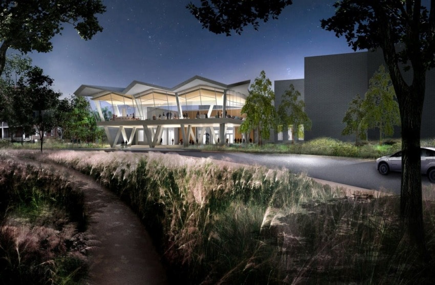 Modern architectural building at night surrounded by illuminated trees and grass under a starry sky.