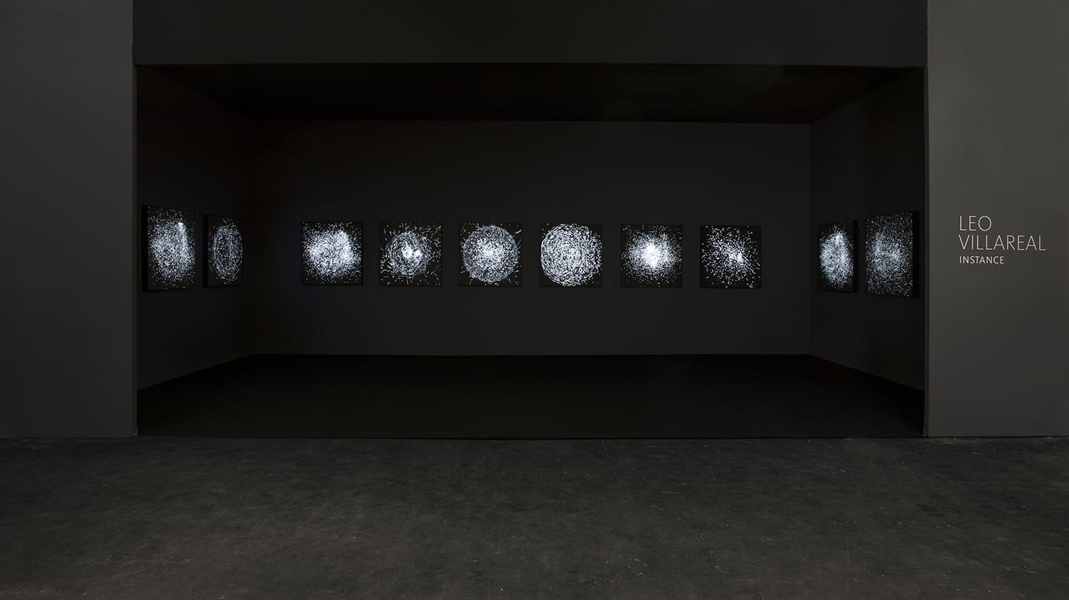 Art installation with a series of illuminated, intricate patterns on a dark wall by Leo Villareal titled Instance.
