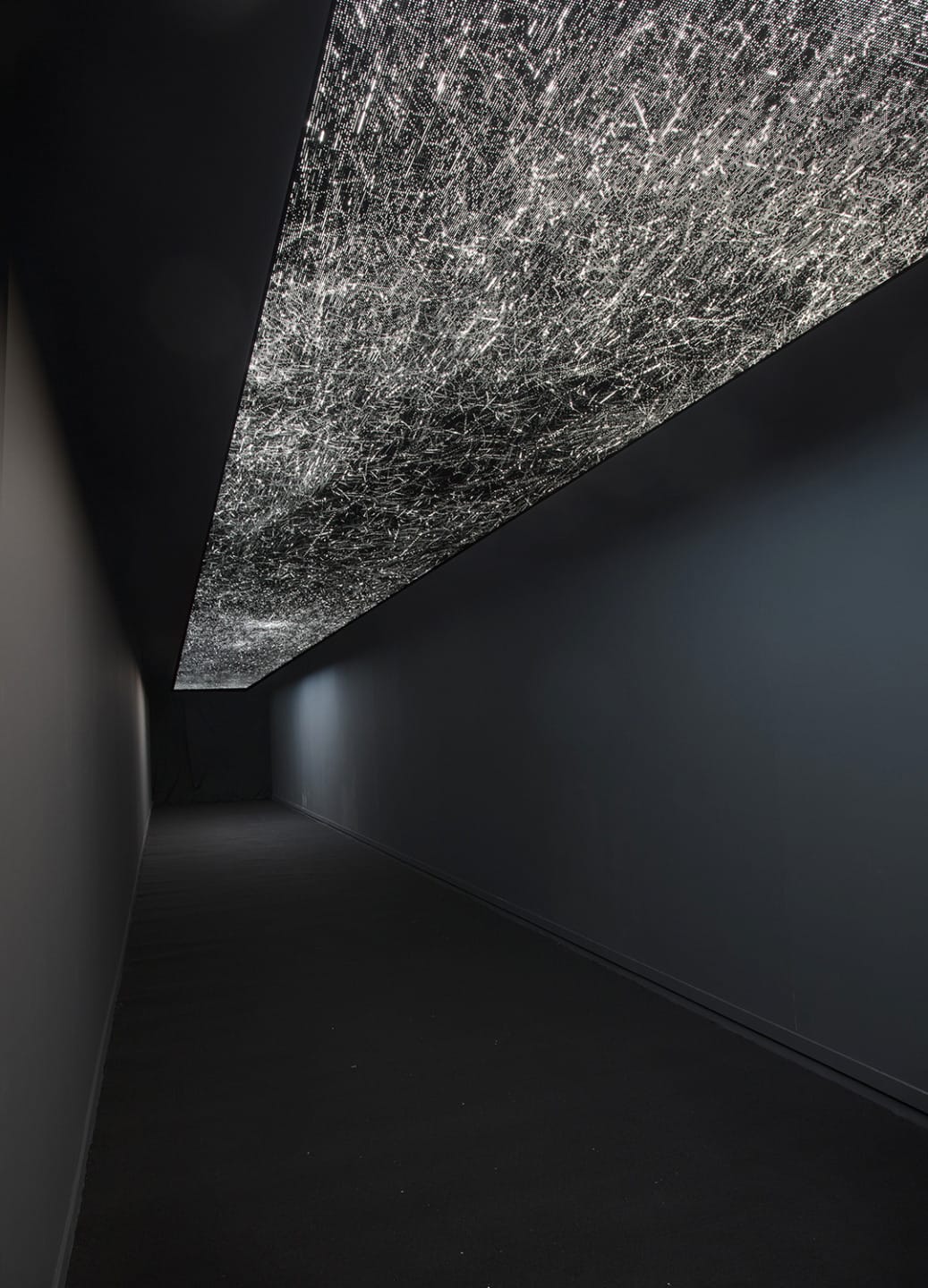 Dark hallway with an illuminated textured ceiling, creating a dramatic contrast and modern ambiance.