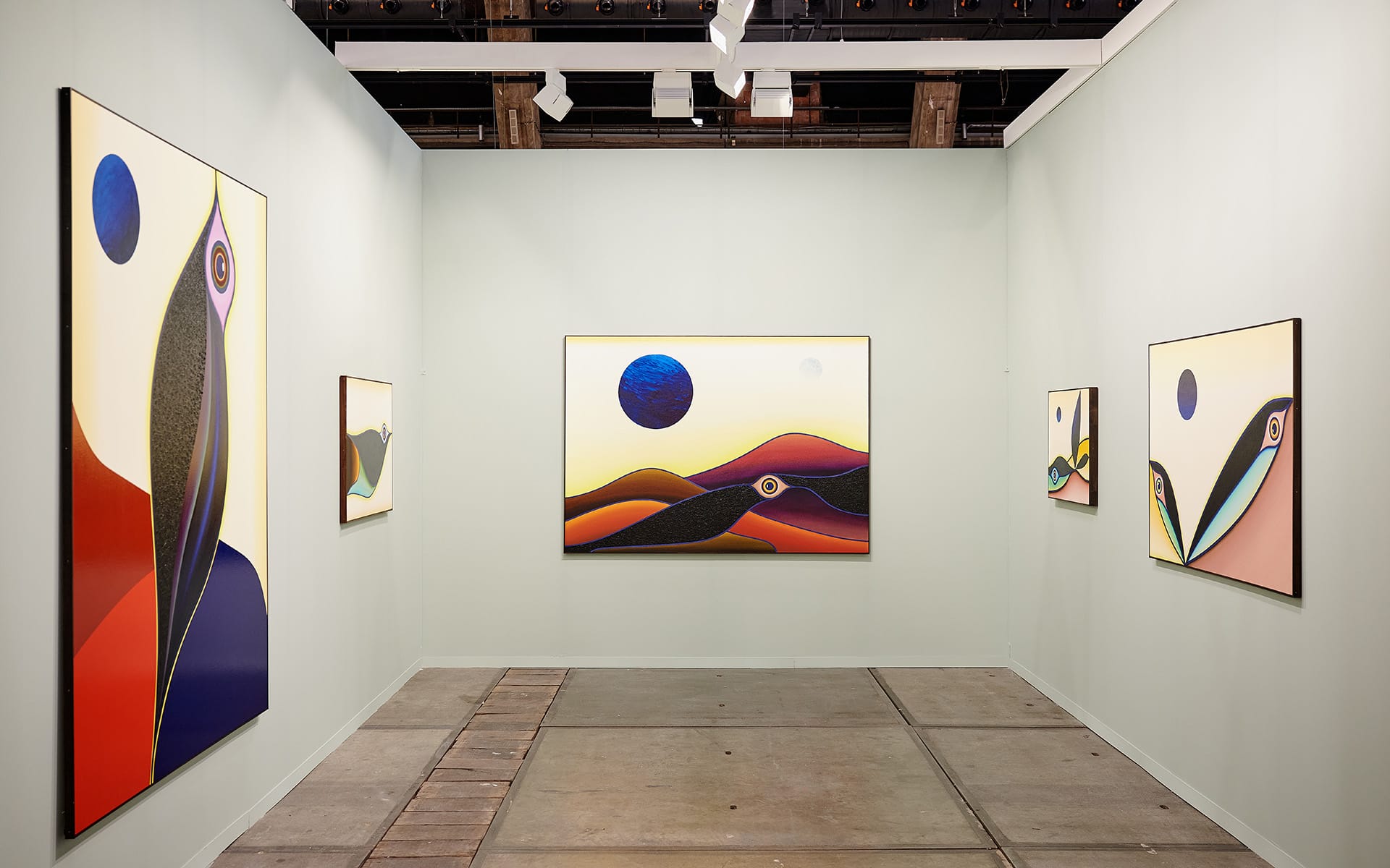 Art gallery with abstract landscape paintings on light green walls displaying vibrant colors and bold shapes.