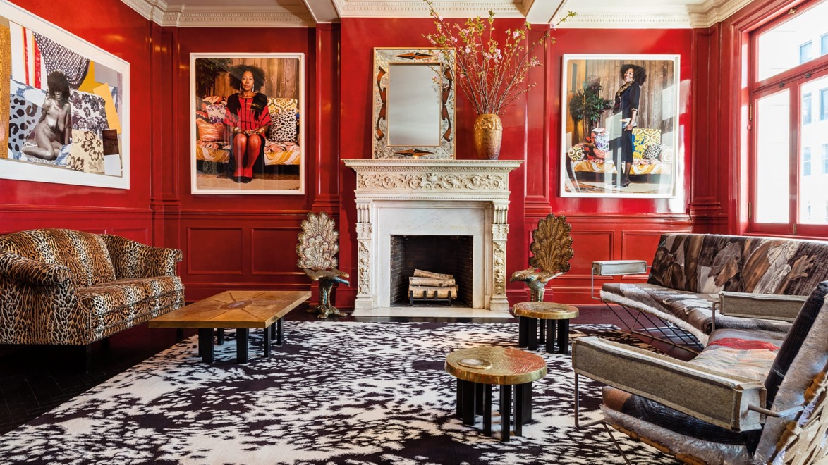 Elegant living room with red walls, patterned furniture, a fireplace, large art pieces, and a bold black and white rug.
