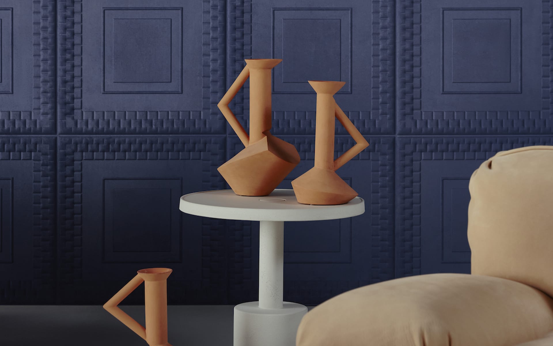 Modern clay vases on round white table with dark blue textured wall background and beige armchair in contemporary setting.