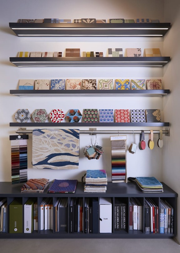Interior design studio display with fabric samples, color swatches, and design tools neatly arranged on shelves and a desk.