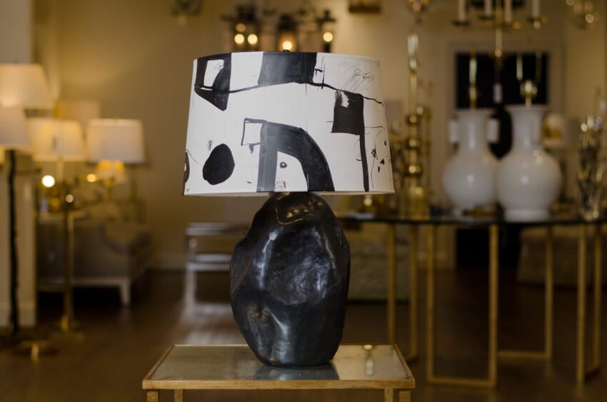 Modern table lamp with abstract black and white lampshade on a stone-like base, displayed in a well-lit store.