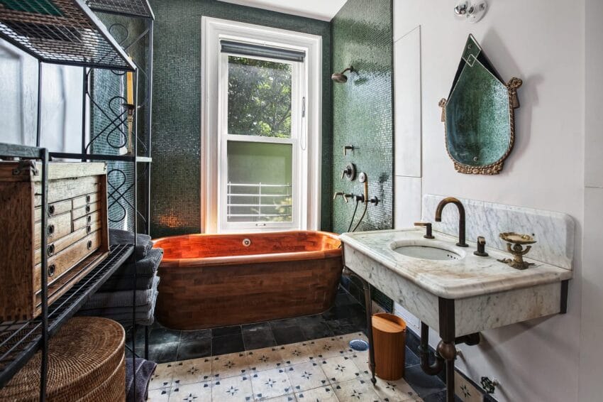 Vintage-style bathroom with a wooden tub, green tiled walls, marble sink, and a window with sunlight streaming in.