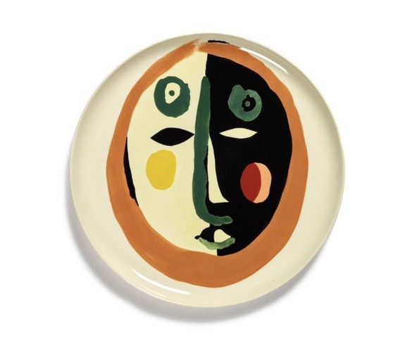 Ceramic plate with modern abstract face design in vibrant colors on white background.