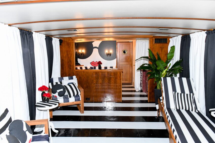 Retro-themed room with striped loungers and black-and-white decor, featuring a bold face mural with sunglasses.