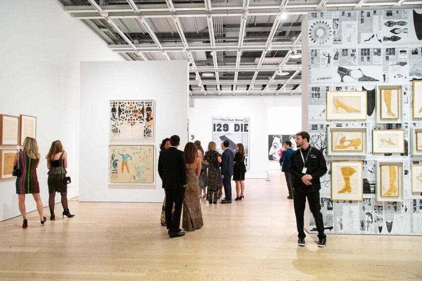 People viewing art exhibits in a modern gallery with paintings and wall graphics