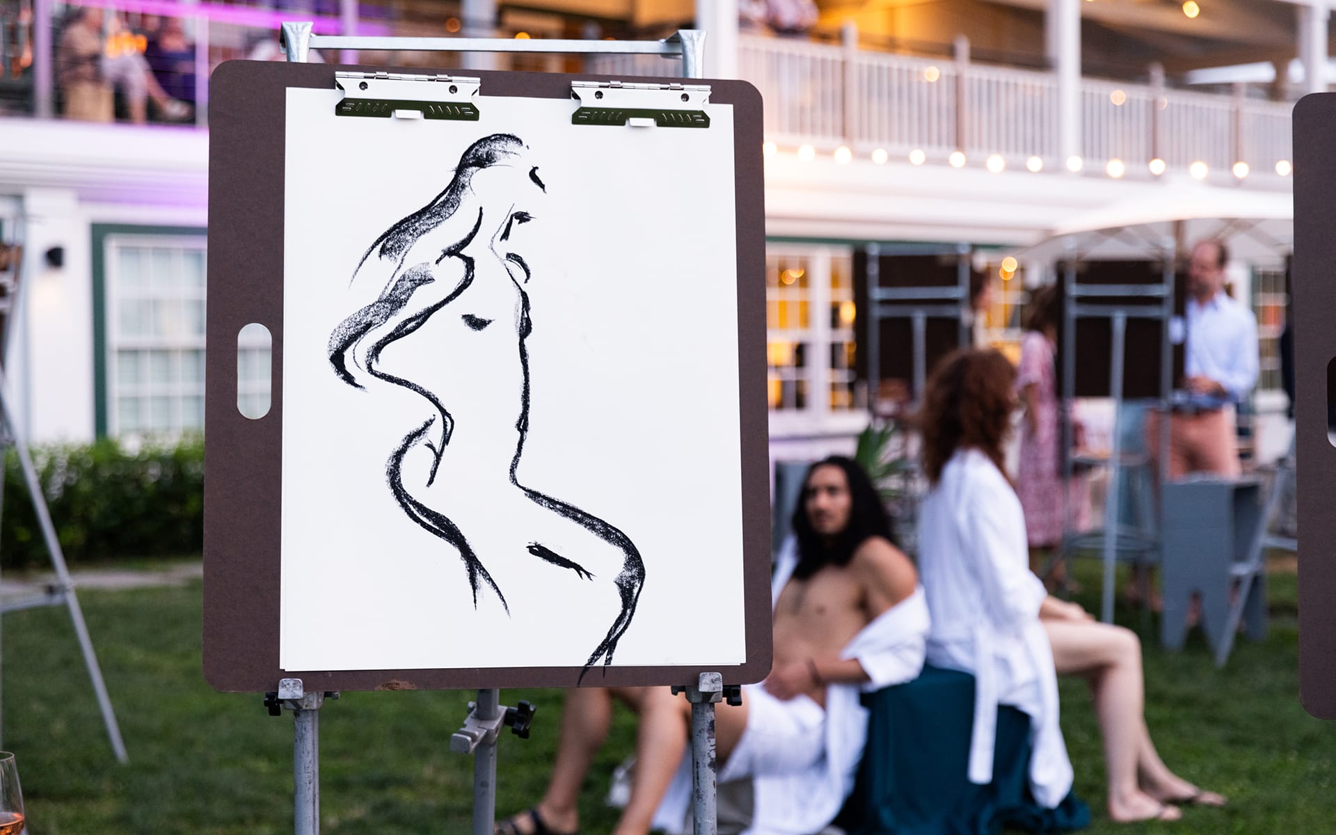 Sketch of a nude figure on an easel in an outdoor setting with people in the background.
