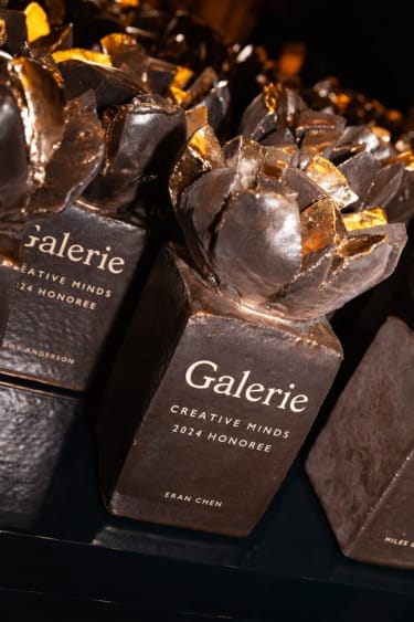 Award trophies labeled "Galerie Creative Minds 2024 Honoree" with a gold and black floral design on top.