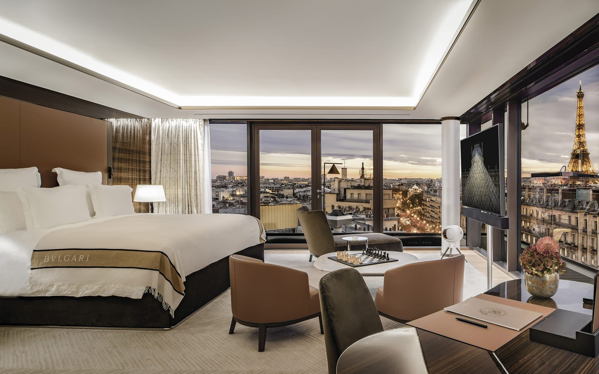 Luxurious hotel room with a view of the Eiffel Tower, elegant furnishings, and large windows overlooking the cityscape.