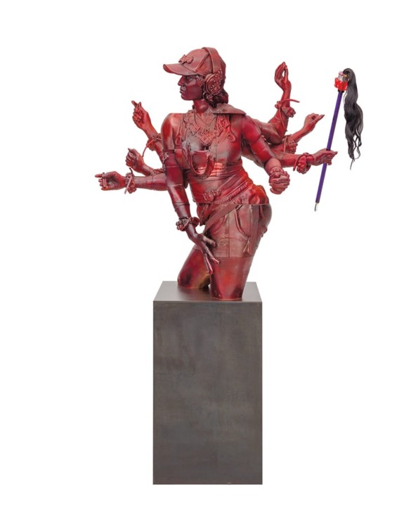 Red sculpture of a person with multiple arms wearing a cap and holding a wand with hair, posed on a pedestal against a white background.