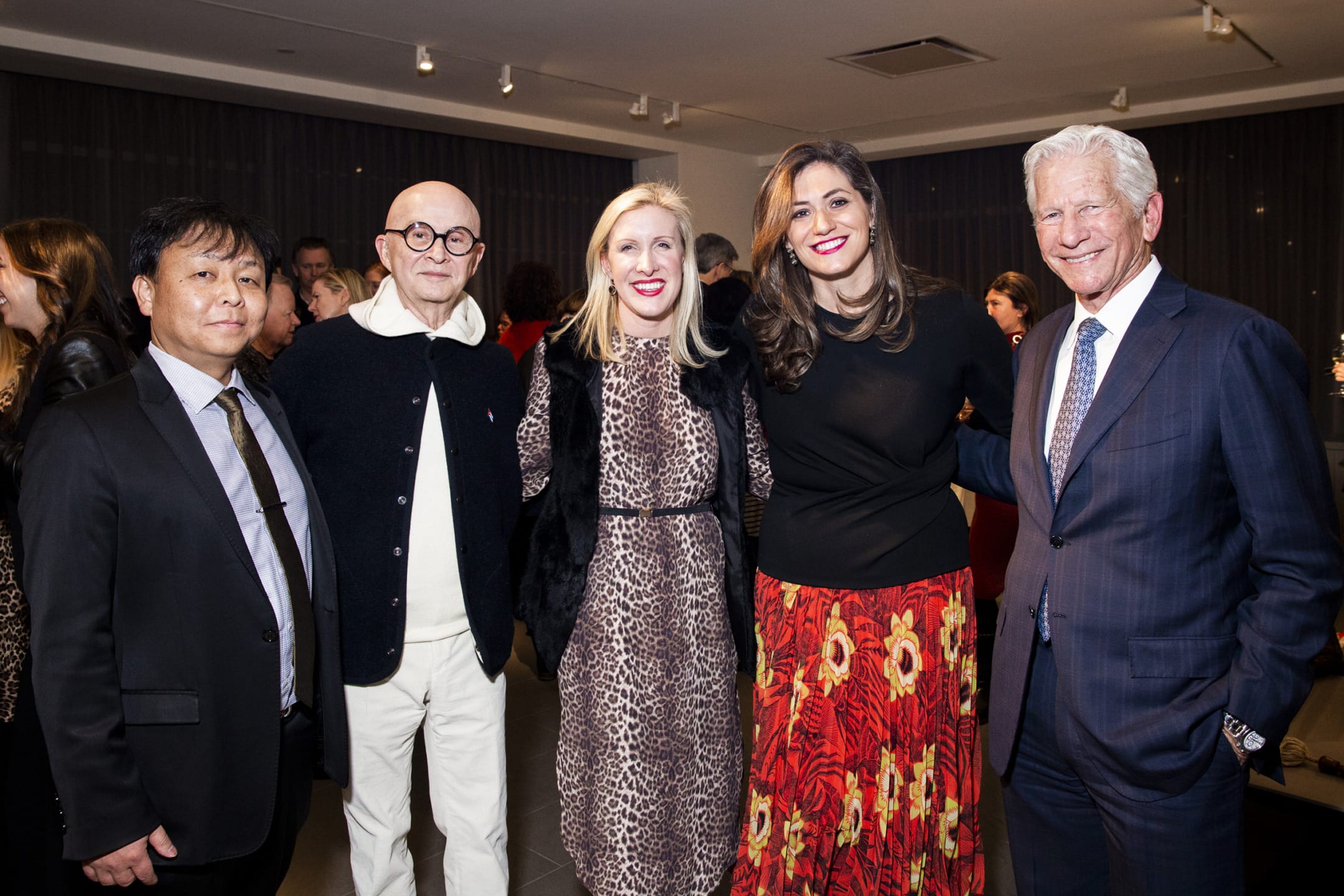 A group of five people posing together at a formal event, all smiling and dressed in elegant attire.