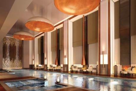 Luxurious indoor swimming pool with elegant lounge chairs, golden ceiling lights, and a waterfall feature in a sophisticated setting.