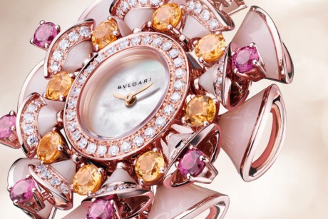 Luxurious pink and gold flower-inspired wristwatch with gemstones, pearl face, and intricate design.