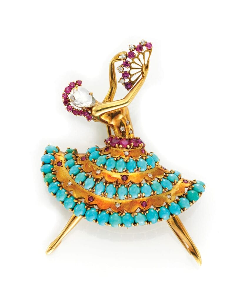 Vintage gold and turquoise brooch shaped like a dancer with a fan and adorned with gemstones.