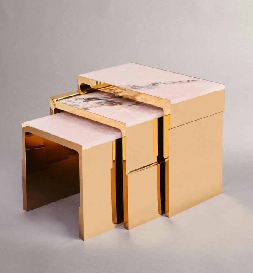 Modern geometric gold nesting tables with marble tops on a neutral background.