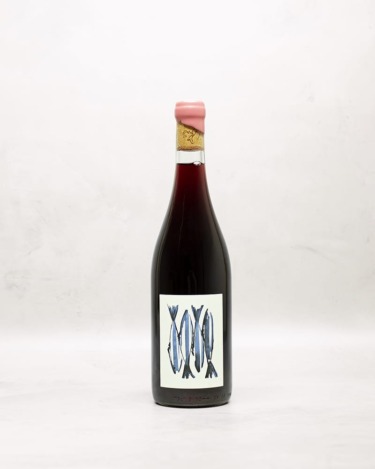 Red wine bottle with artistic label featuring blue fish illustrations on a light background.