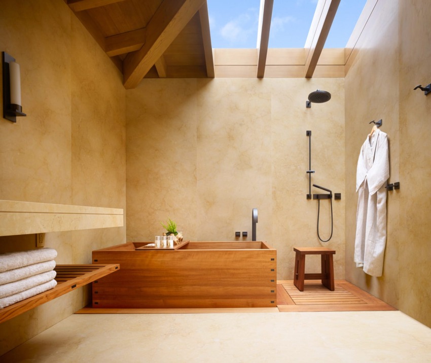 Zen-style bathroom with wooden bathtub, indoor plants, and a skylight. Towel rack and shower area visible.