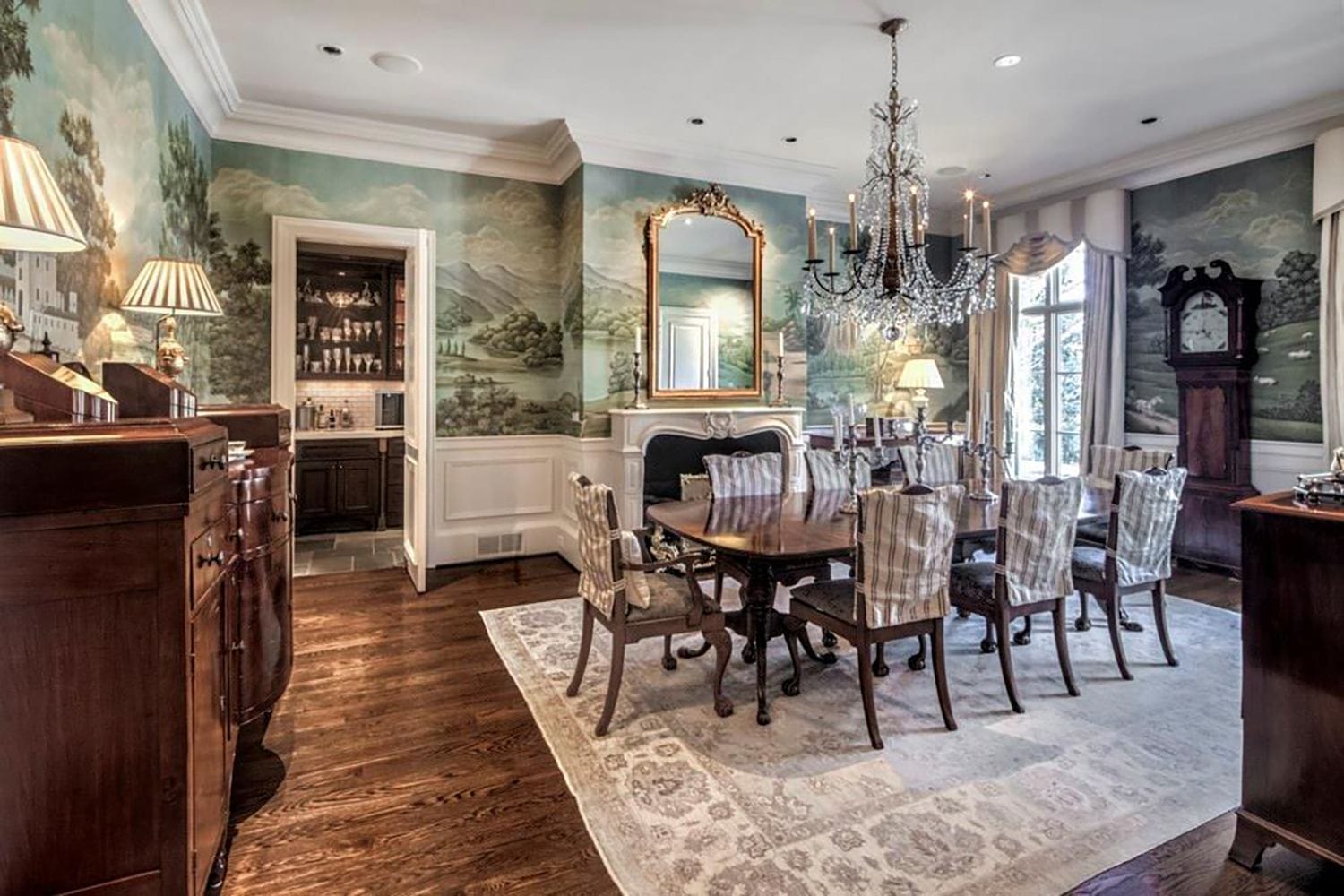 Elegant dining room with wooden table, patterned chairs, chandelier, and mural walls creating a classic ambiance.