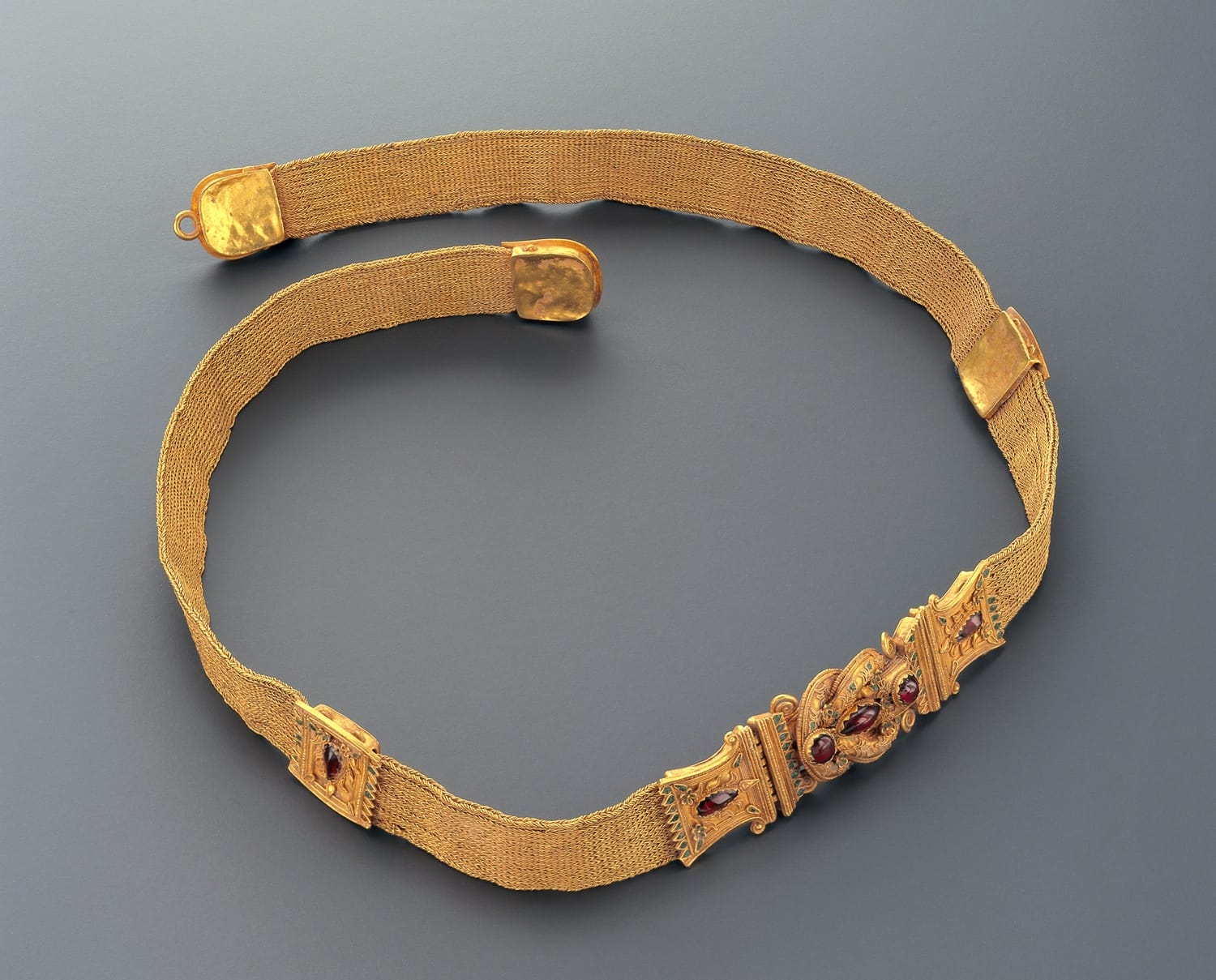 Ancient gold belt with intricate detailing and gemstone accents displayed on a neutral background.