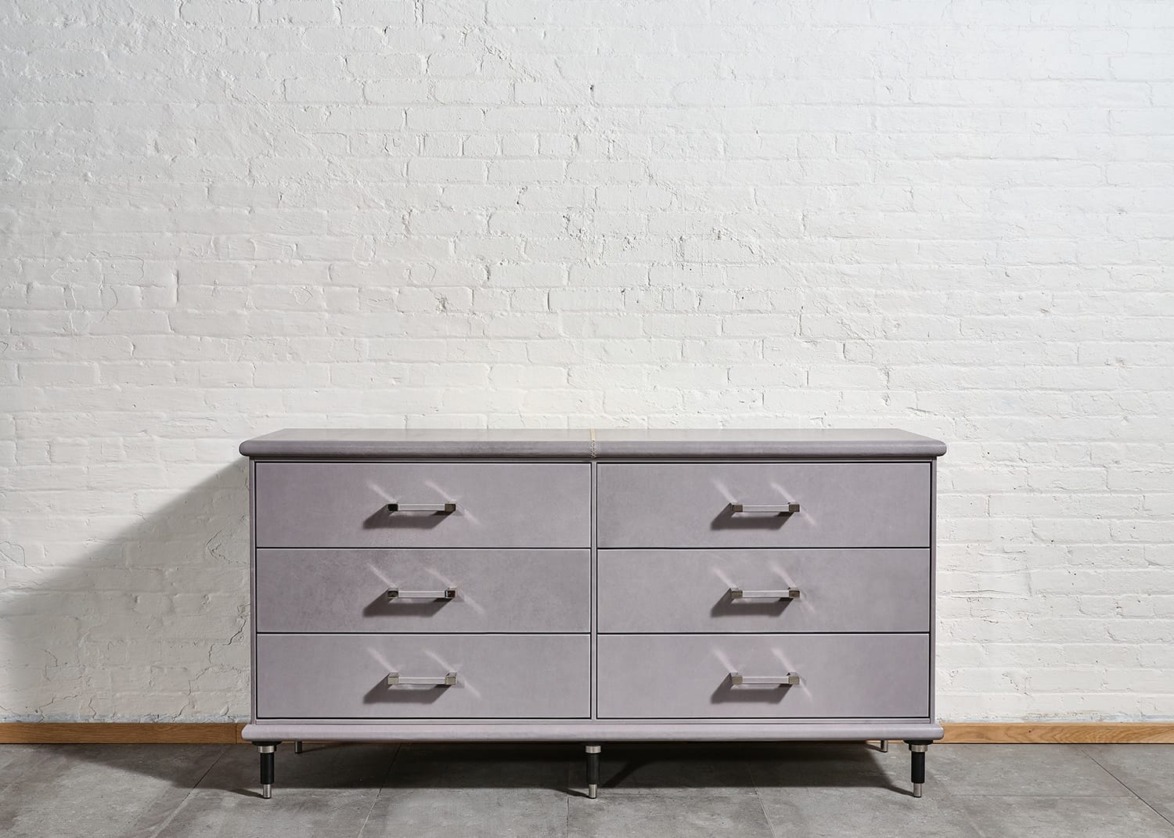 Gray six-drawer dresser against a white brick wall on a wooden floor