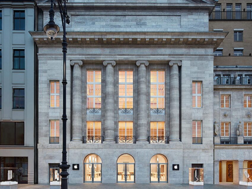 Elegant building facade with tall columns and arched windows illuminated at night, featuring classic architectural details.