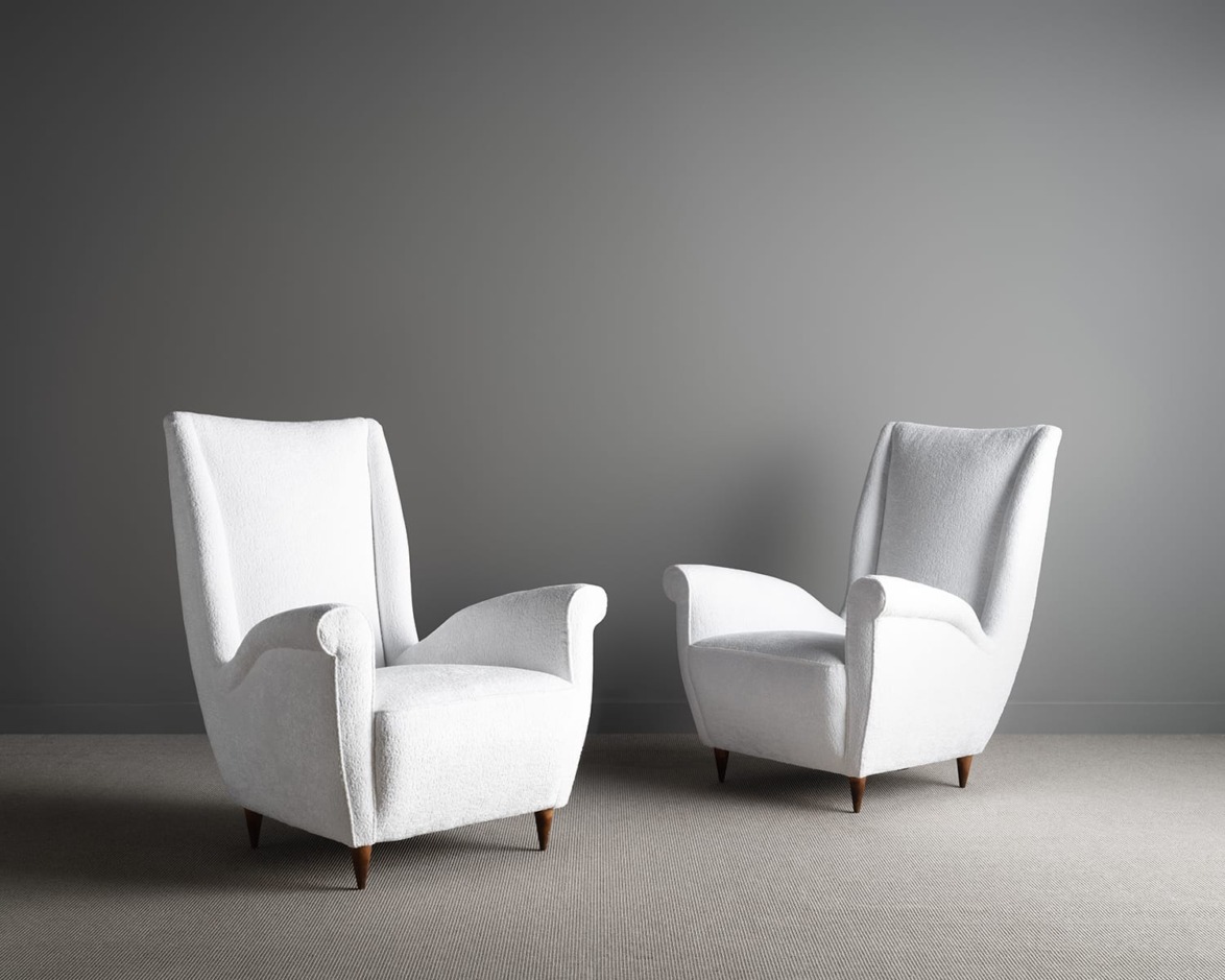 Two white armchairs on a gray carpet against a neutral gray wall.