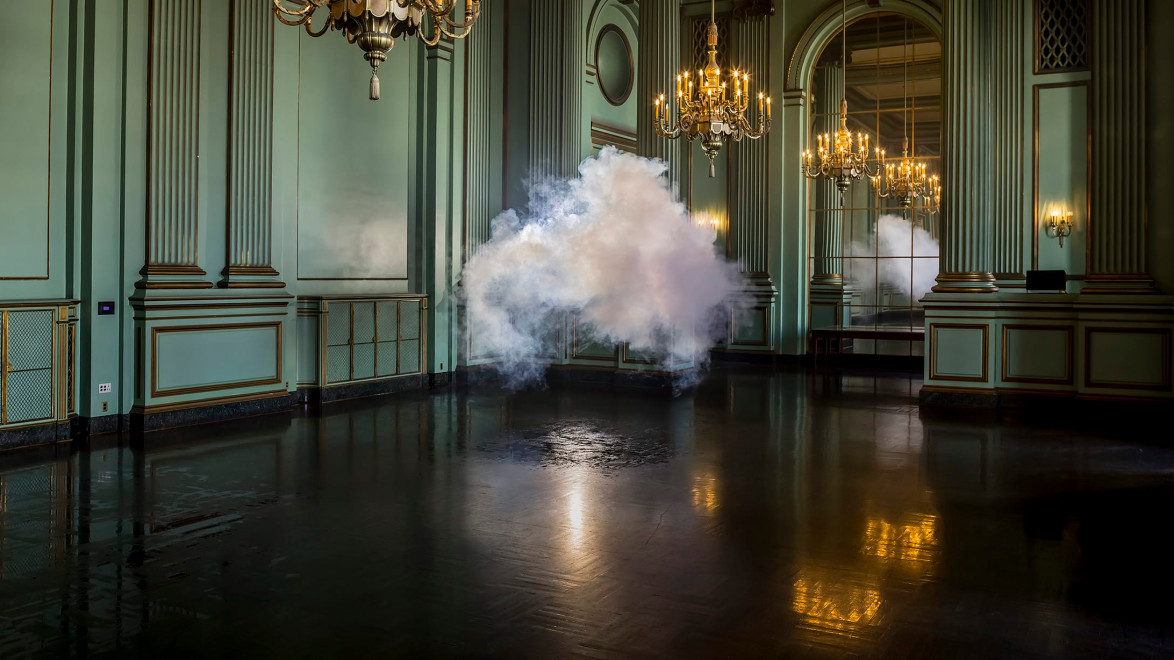 Cloud of smoke hovers inside an elegant, ornate room with chandeliers and large mirrors reflecting the scene.