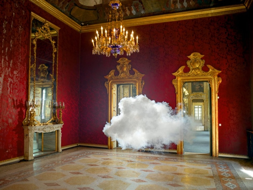 Cloud hovering in an opulent, red-walled room with golden mirrors, ornate details, and a chandelier hanging from the ceiling.