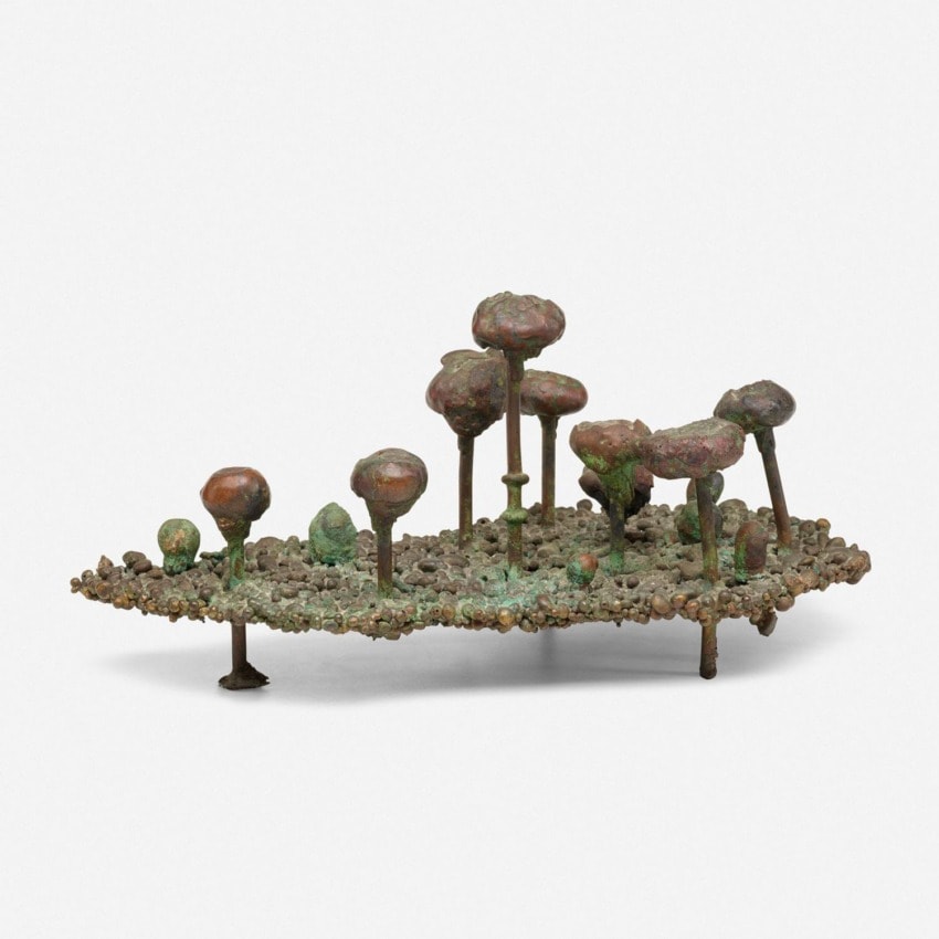 Sculpture resembling a small island with mushroom-like structures on a textured base, made from metal with a patina finish.