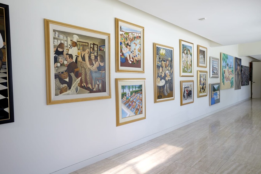 Gallery wall displaying various framed paintings in a modern, brightly lit room with a light marble floor.