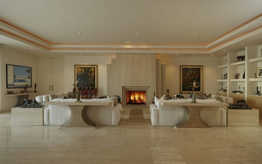 Luxurious living room with stone fireplace, art pieces, and elegant sofas, creating a warm and sophisticated atmosphere.