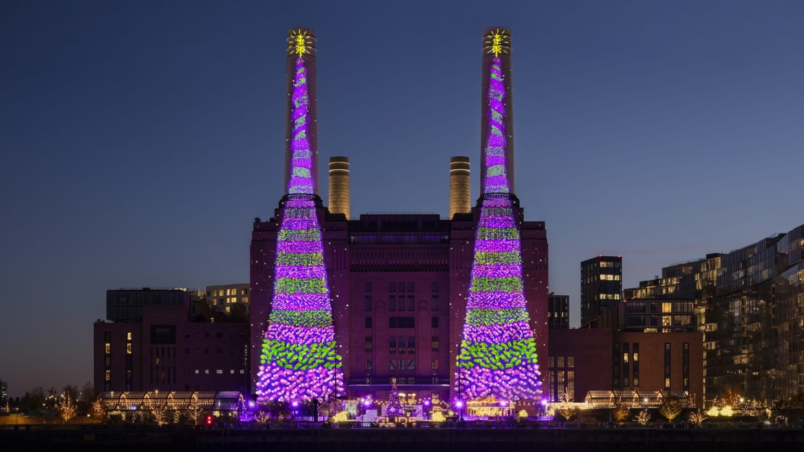 Battersea Power Station illuminated with vibrant purple and green lights during an evening event.