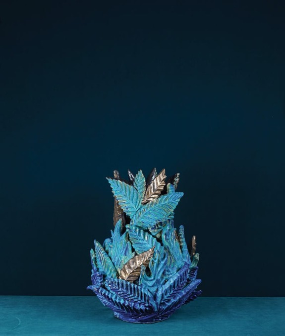 Decorative blue and gold ceramic sculpture with leaf-like patterns against a dark blue background