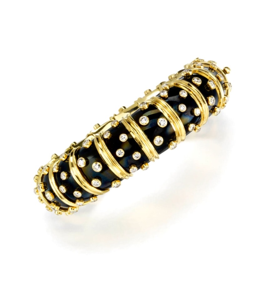 Gold and black bracelet adorned with sparkling white gemstones on a plain white background