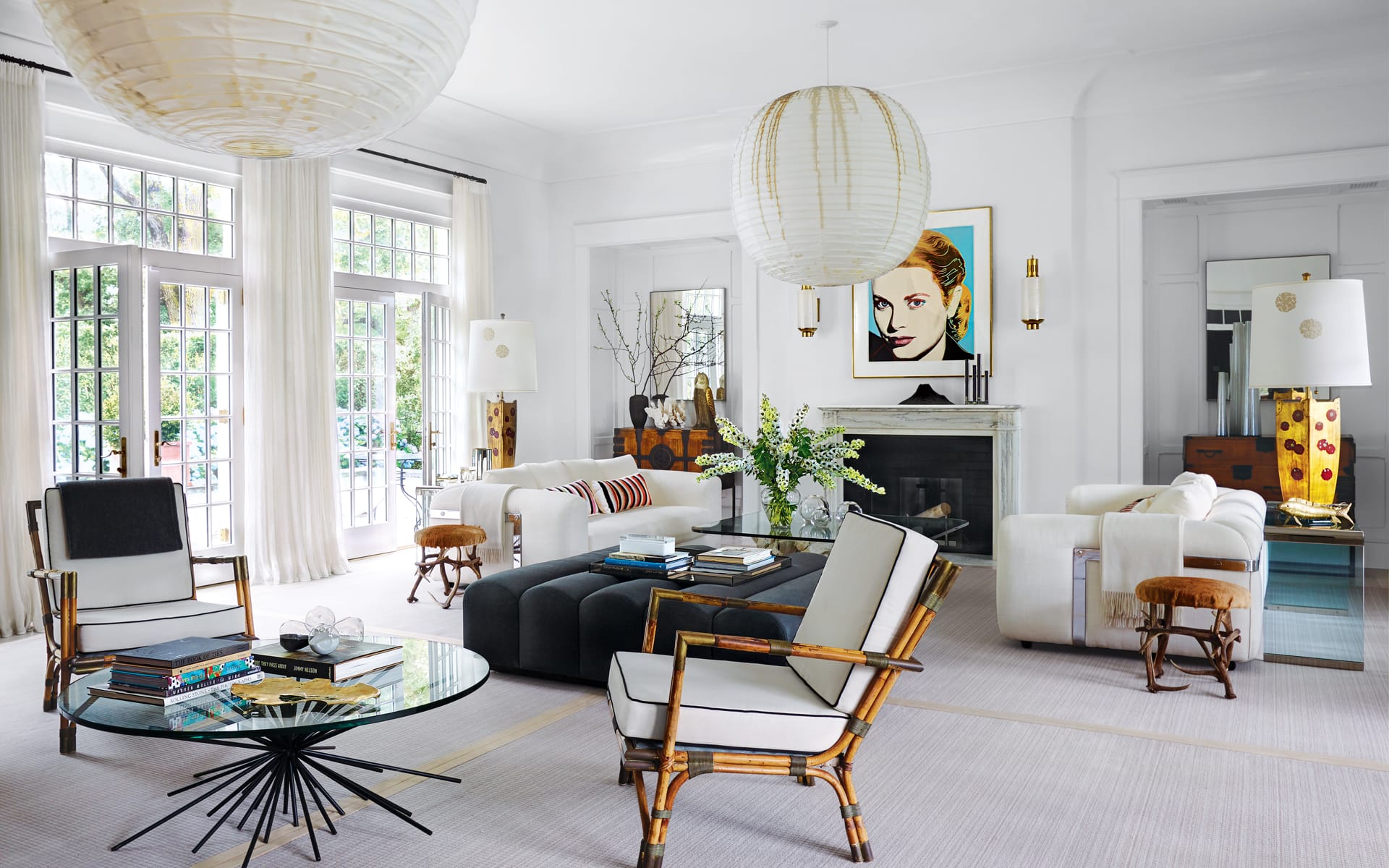 Modern living room with large windows, white sofas, artistic decor, and a round glass coffee table on a light rug.