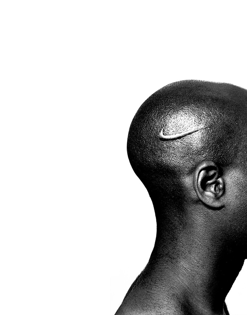 Shaved head with small Nike logo, black and white photography focusing on texture and branding.