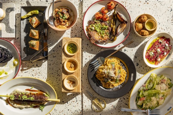 Aerial view of various gourmet dishes on a table, including pasta, meats, and salads.