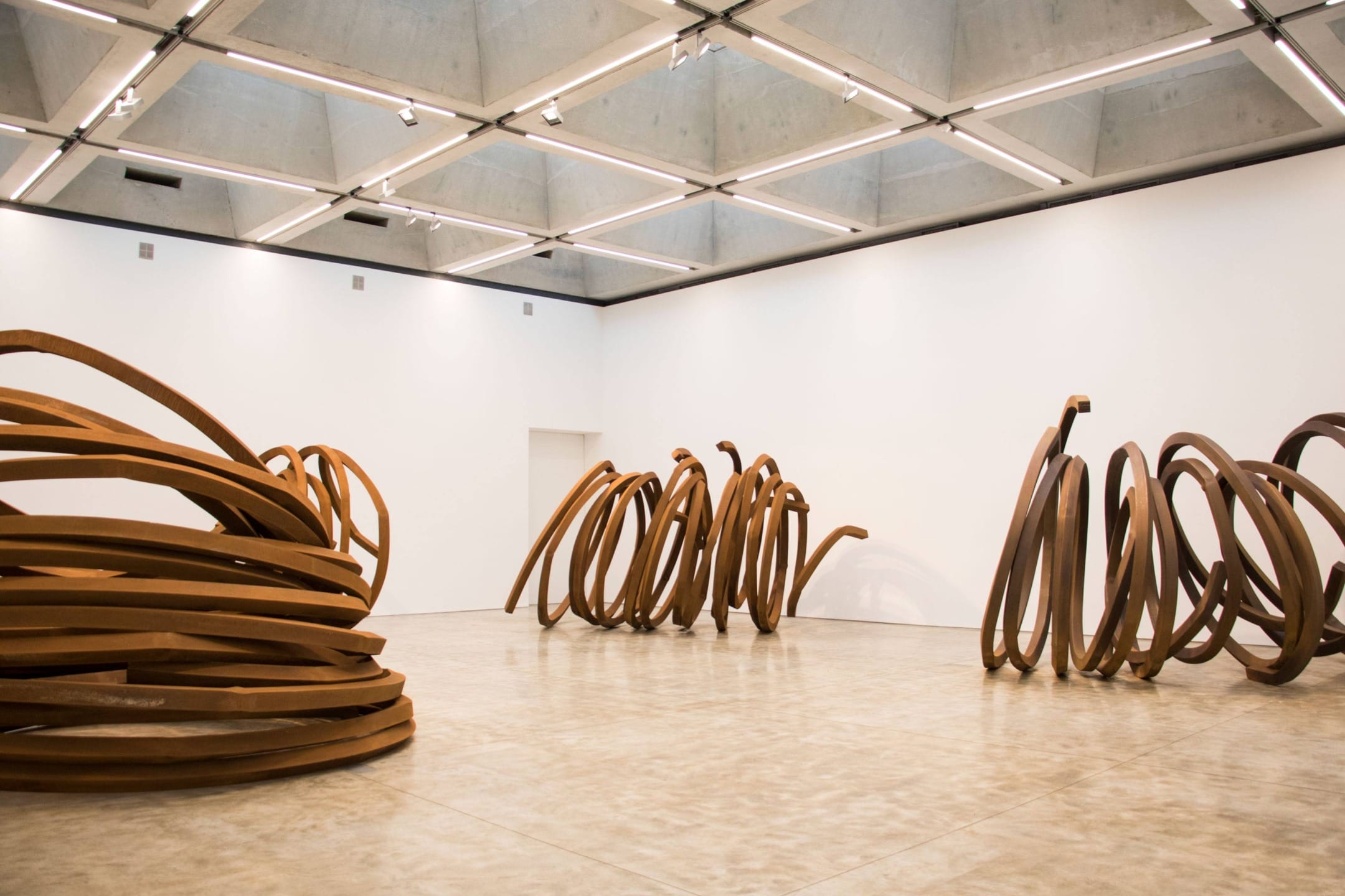 Abstract metal sculptures in a modern art gallery with high ceilings and bright lighting.